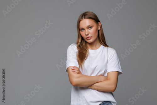 Young woman smiling and crossing her arms looking like a boss on white background
