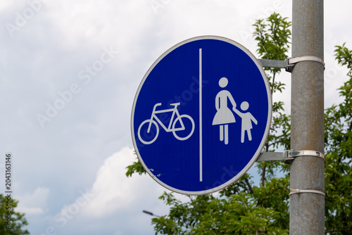 Bicycle and pedestrian sign guiding safe passage for families in a green, urban setting