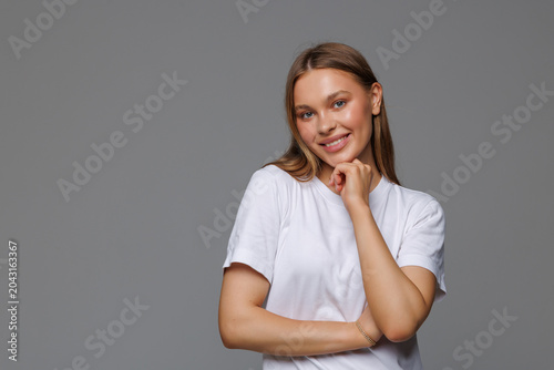 Young woman is thinking with her hand on chin isolated on gray background
