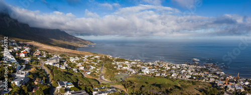 Photos Aerial panorama of Cape Town's Atlantic Seaboard shows Twelve Apostles with low clouds, Camps Bay and Clifton curving to the right, white houses, coves, and calm ocean