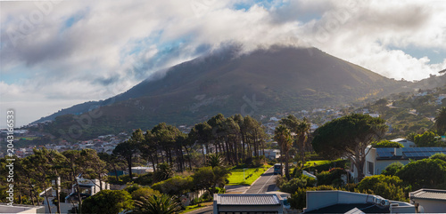 Tableau sur toile Sunlit suburban streets and white houses in Cape Town, South Africa, lead toward a cloud brushed mountain resembling Lion's Head, with soft late afternoon light