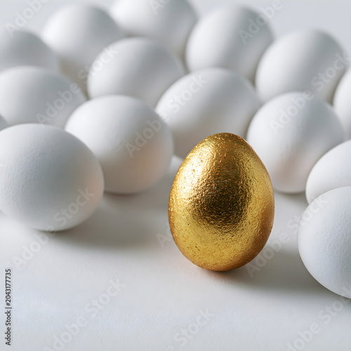 Golden egg standing out among many white eggs.