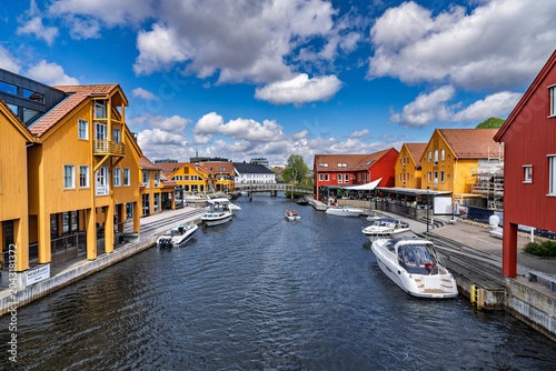Colorful waterfront houses reflecting in calm harbor under stormy sky at dusk, Kristiansand, Norway