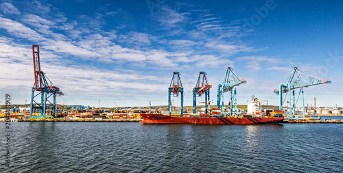 Cargo Ship and Container Cranes at Busy Industrial Port Under Blue Sky and Calm Water, Gothenburg, Sweden