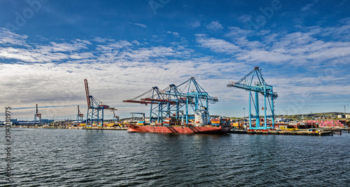 Cargo Ship and Container Cranes at Busy Industrial Port Under Blue Sky and Calm Water, Gothenburg, Sweden