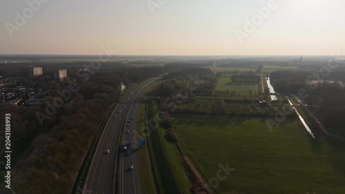 Low aerial flyover of highway traffic and Dutch countryside at sunset