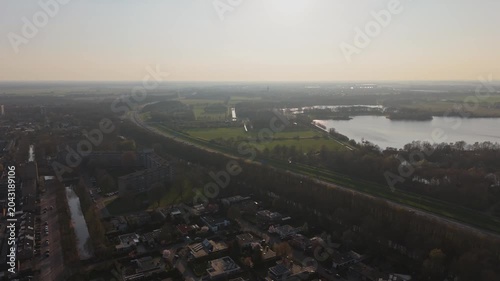 Descending aerial approach over highway and Dutch town at sunset