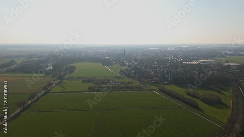 Wide aerial orbit of Dutch town and green countryside at sunset