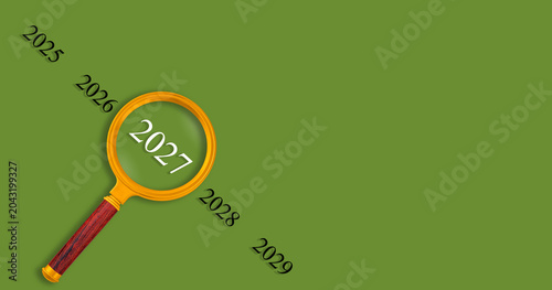 Vision 2027 concept with magnifying glass on Green background, looking into the future