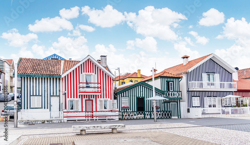 Iconic wooden houses with colorful vertical stripes under a clear blue sky in Costa Nova, Portugal.
