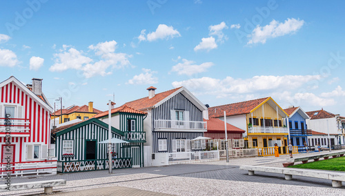 Iconic wooden houses with colorful vertical stripes under a clear blue sky in Costa Nova, Portugal.