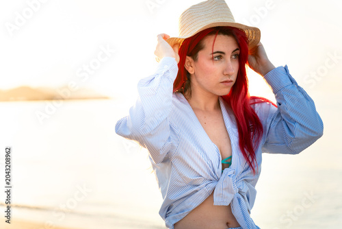 Young woman with red hair enjoying a beach vacation during sunset