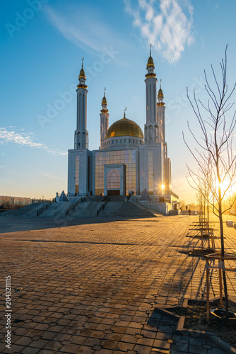 Nur Gasyr Mosque in Aktobe at sunset with a bright yellow sun, Kazakhstan