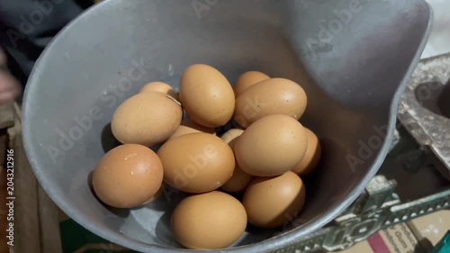 Weighing fresh chicken eggs on a scale close up