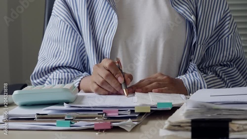 Adult office worker reviewing paperwork and reports at desk, representing document management, business administration, accounting workflow, compliance review, deadline pressure, and productivity.