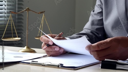 Business attorney signing legal agreement at office desk with balance scale, highlighting corporate law, regulatory compliance, confidential paperwork, and client support.