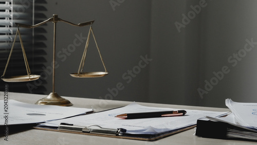 Fotografía Golden scales rest on a cluttered desk