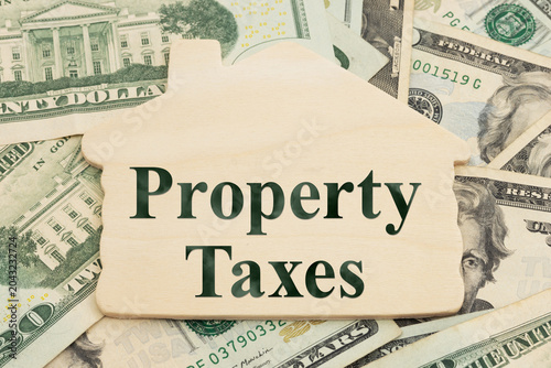 фотографія Property Taxes text on a wood house on twenty dollar bills for annual home tax