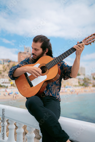 Passionate Spanish Guitar Player Seated with Ocean and Urban View