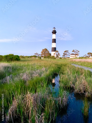 Bodie Island Lighthouse stands above a peaceful marsh landscape on North Carolina’s Outer Banks, with winding tidal waters reflecting the soft evening light.