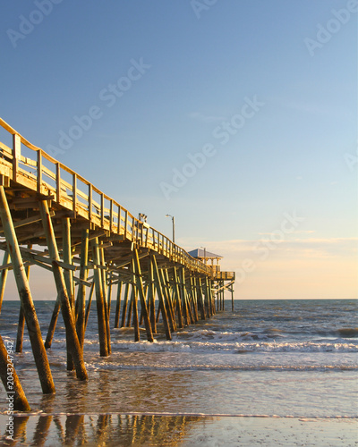 Warm evening light illuminates the Atlantic Beach Fishing Pier as gentle waves roll onto the shoreline along North Carolina’s Crystal Coast.