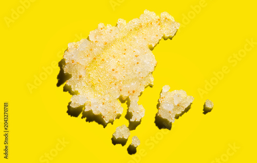 Natural body scrub with sea salt on bright yellow background. Smear of exfoliating organic facial scrub cosmetic product, scrubber. Salt or sugar scrub swatch for skin care, texture. Skincare Top view