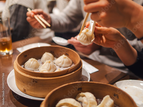 woman hands scoops up dim sum with a spoon and chopsticks at the party
