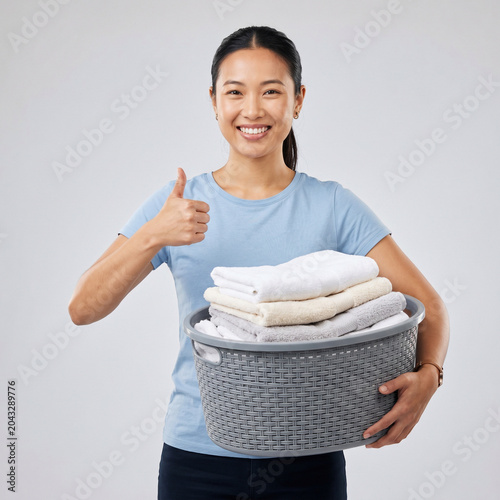 Happy Asian Woman Holding Fresh Laundry and Showing Approval Gesture