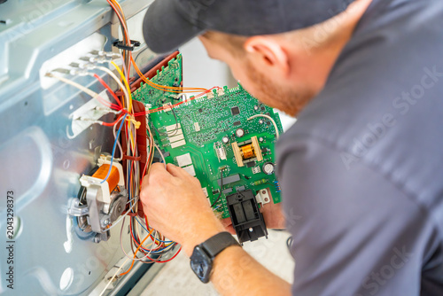 Vászonkép Appliance technician replacing faulty electronic control board inside electric oven