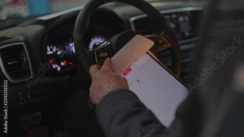 His hand is carefully touching the screen to navigate through the car scanning software and check for errors.The male technician is scanning the vehicle.He holds a digital diagnostic device.