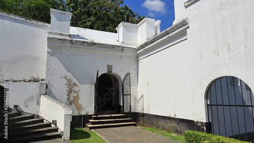 Obraz na plátně An arched doorway with a gate made of black iron bars is set into the boundary wall of an old building