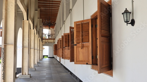 Картината върху платно A row of brown wooden windows appears open on an old building.