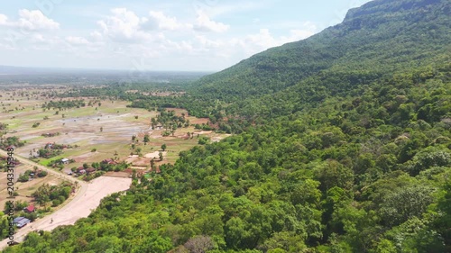 Aerial footage of the distinctive flat-top mesa formation near Khamtay Cave, Attapeu Province, southern Laos. The drone glides past the forested tabletop mountain revealing the wide agricultural valle
