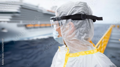 Health worker in protective gear with cruise ship in background during maritime safety drill