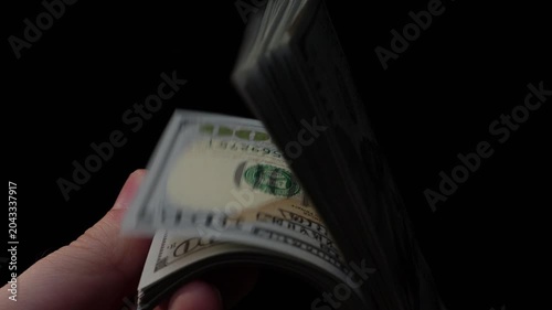Close-up of hand flipping through stack of U.S. hundred dollar bills in slow-motion
