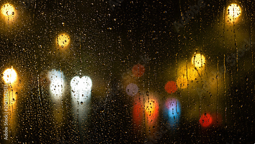 Cuadro en lienzo Raindrops on window glass with blurred city lights at night, creating moody urba