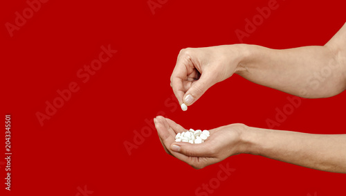 Hand puts pill into palm full of medication on red. Depression, anxiety and other mental disorders.