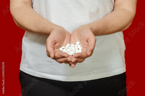 Fotografie Rerson holding handful of pills on red