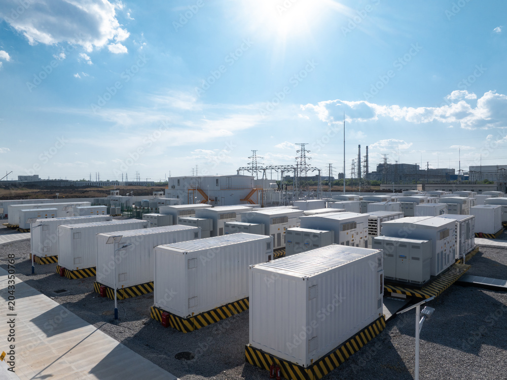 Obraz premium White containerized energy storage systems arranged in an outdoor power station facility