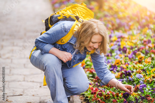 Bild auf Leinwand Smiling mid adult woman in denim jacket crouching by flower bed with pansies