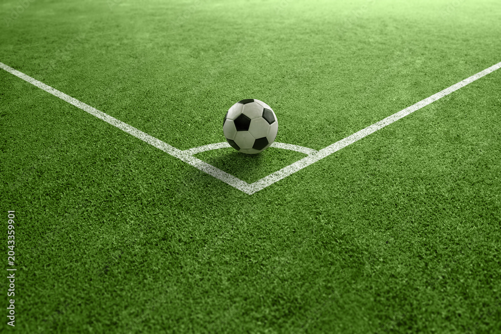 Fototapeta premium Classic black and white soccer ball placed on the corner kick line of a green turf field