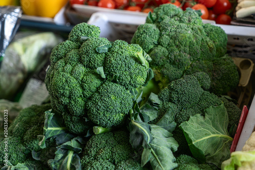 Fresh raw broccoli heads on display at a local farmers market. Healthy food background with crisp vegetables for vegan lifestyle and culinary concepts