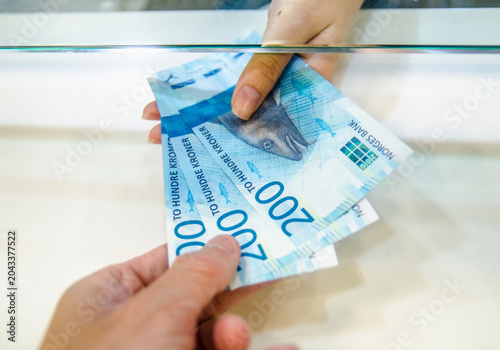 Bild auf Leinwand Hands exchanging norwegian kroner banknotes across a glass counter in a transact