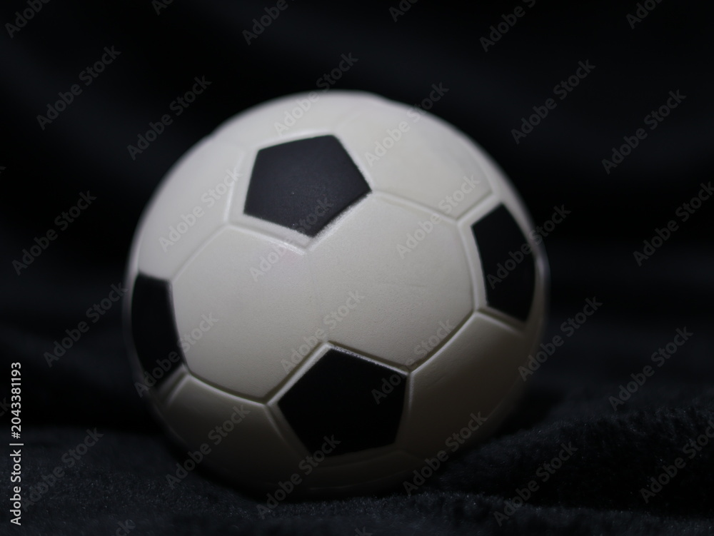 Fototapeta premium Una toma de cerca de una pelota o balón de fútbol con luces en un fondo negro con algo de desenfoque 