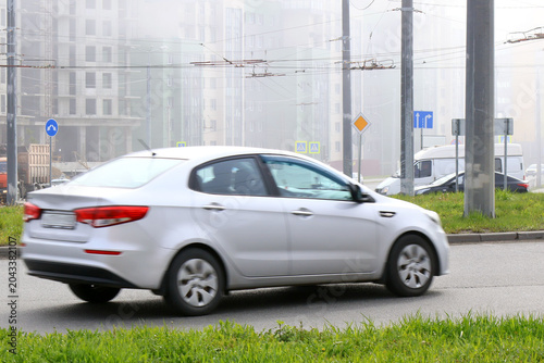 Motion blur of a silver sedan navigating through misty urban traffic