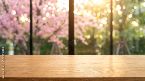 Empty wooden table mockup in blurred pink cherry blossom garden background with warm sunset light and bokeh
