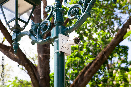 Camera mounted on street lamp in a park during daylight