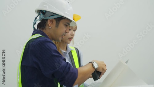 Engineer Hard Hat Blueprint Planning Construction Site with Colleague for Safety Inspection, Indoor Worksite Communication, Reflective Vest, Laptop Teamwork, Project Coordination, Professional
