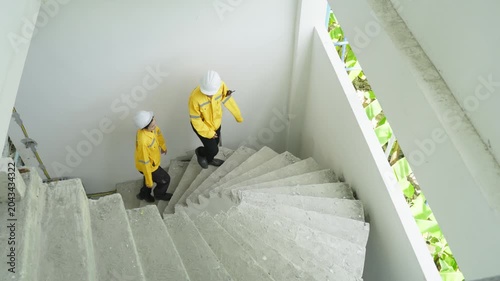 Construction worker staircase safety helmet yellow jacket concrete stair indoor teamwork engineering building site inspection concrete stairwell industrial climbing pair worker safety