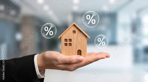 Hand holding wooden house model. Real estate investment, mortgage interest rates, and property market